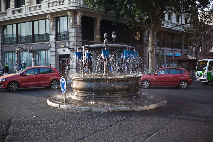 Installation of buckets with holes over a public Fountain which alter the water´s expected direction and sound. Madrid, Spain. Photo © SpY.