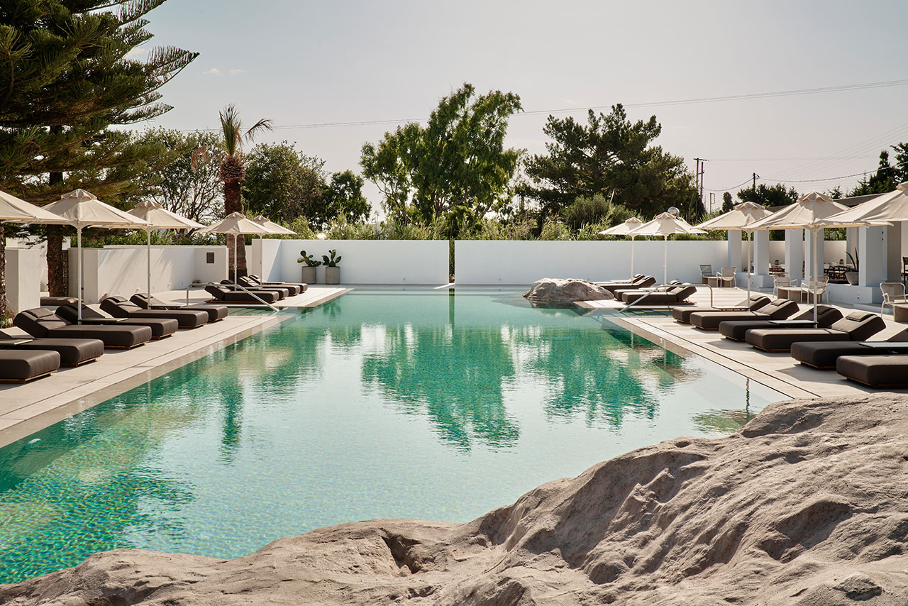 The cruciform pool is intercepted by rock formations echoing the local landscape. © Parīlio a member of Design Hotels™ | Kolympithres,Naoussa Paros, Greece.Photo by Claus Brechenmacher &amp; Reiner Baumann. Courtesy of Parīlio.