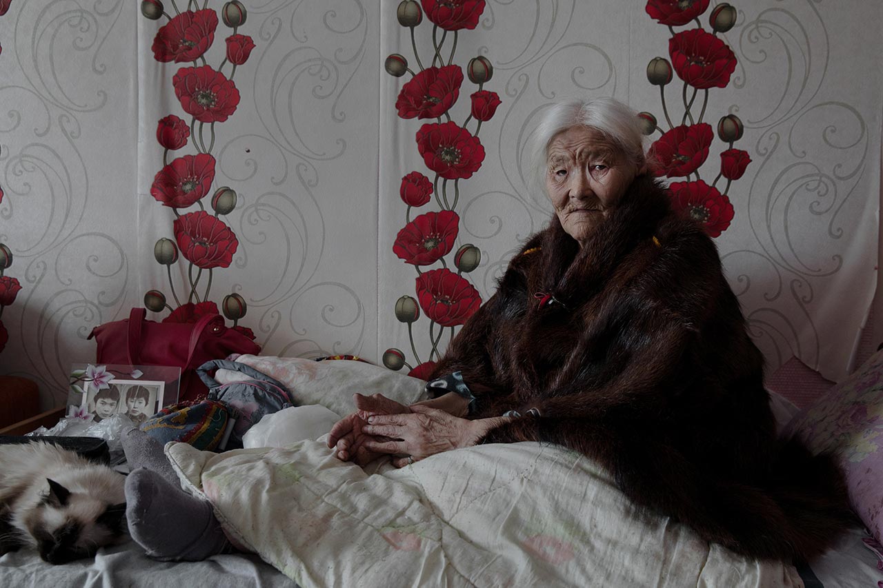 Necla Audi (Born. 1928). Yar-Sale, Yamalo-Nenets Autonomous Okrug, Russia. Although Necla was 89 when this portrait was taken, she declared that she insists on returning to live with the migrating community. At the far left of her bed, a picture of her two sons, taken when they were young. Now, both of them are herders in the tundra.
Photo © Oded Wagenstein.